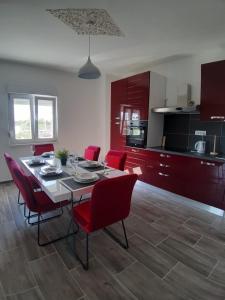 a kitchen and dining room with a table and red chairs at Holiday House Ivan in Donji Zemunik