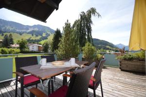 a wooden table and chairs on a deck with mountains at Haus Alpenblick in Oberjoch