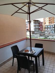 una mesa y sillas en un balcón con sombrilla en B&B Nonna Maria en Lamezia Terme