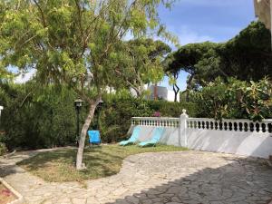 twee stoelen en een boom naast een wit hek bij Chalet La Costa in Chiclana de la Frontera