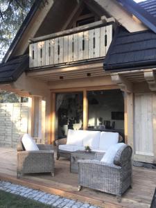 a patio with wicker furniture on a wooden deck at Domek Koliba pod Smrekami in Zakopane