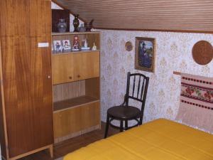 1 dormitorio con silla, cama y estante en Agancs Vendégház, en Balatonszemes