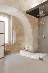 a bathroom with a glass shower in a brick wall at Hydria Rooms in Matera