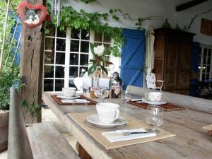 a wooden table with plates and glasses on it at Chambres d'Hôtes de Pesquès in Termes-dʼArmagnac