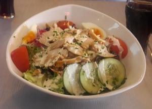 a bowl of salad with chicken and vegetables on a table at Hotel MMG in Tbilisi City