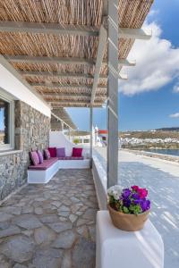 皮沙羅的住宿－Mykonos Azure，庭院配有紫色和白色家具和鲜花