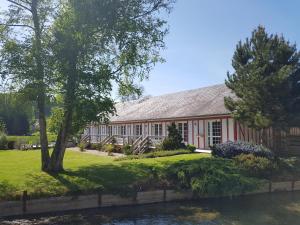 un bâtiment rouge avec une rivière devant lui dans l'établissement Auberge De La Durdent, à Héricourt-en-Caux