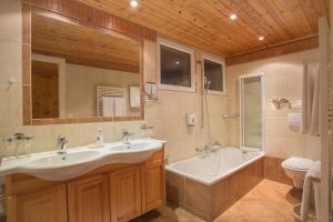 un bagno con due lavandini, una vasca e un WC di Hotel Ad'Eldorado a Crans-Montana