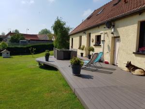 un perro tirado en una terraza de madera junto a una casa en Vieille Fermette BnB chambre prive, en Waben