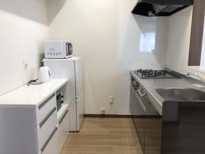 uma pequena cozinha com um lavatório e um frigorífico em TerraceRin YN32 em Tomigusuku