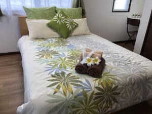 uma cama com duas toalhas e flores em TerraceRin YN32 em Tomigusuku
