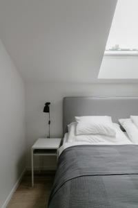 ein weißes Schlafzimmer mit einem Bett und einem Nachttisch in der Unterkunft KRACHER Suite mit Nationalparkblick in Illmitz