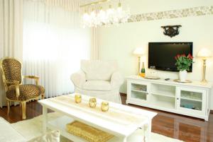 uma sala de estar branca com uma televisão e uma cadeira em Landhotel Christopherhof em Grafenwiesen