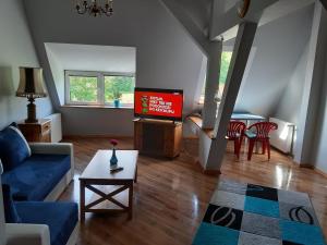 Una sala de estar con un sofá azul y un televisor. en Apartament Błonia, en Szczecin