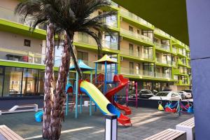 ein Spielplatz mit Rutsche und Palme vor einem Gebäude in der Unterkunft Blue Apartment in Spa n Pool Beach resort in Mamaia Nord – Năvodari