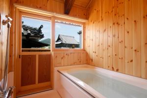 a bath tub in a wooden bathroom with a window at Kariya Ryokan Q in Ako