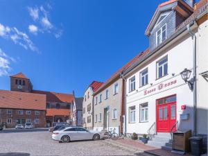 un coche aparcado frente a un edificio con una puerta roja en Altstadt - Apartments, en Waren