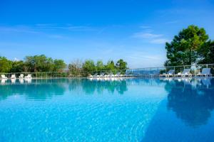 a large pool of blue water with white chairs at VTF Le Castelet in Saint-Aygulf