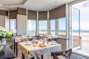 - un restaurant avec des tables et des chaises offrant une vue sur la plage dans l'établissement Hôtel Le Beaufort, à Saint-Malo