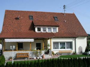 ein Haus mit rotem Dach und zwei Bänken in der Unterkunft Pension Gästeparadies in Kleinkötz