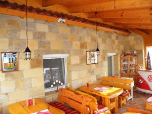 a room with wooden tables and chairs and a stone wall at Pension Gästeparadies in Kleinkötz