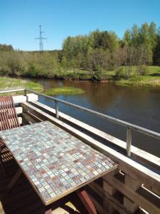 Mosina Vesiveski في Vissi: طاولة وكراسي يجلسون على جسر بجوار نهر