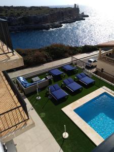 
a patio area with a pool, lawn chairs, and lawn chairs at Hotel Rocamar in Cala Figuera
