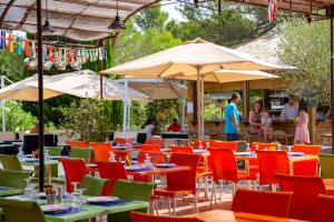 a restaurant with tables and chairs and umbrellas at VTF Le Castelet in Saint-Aygulf