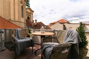 a patio with two chairs and a table on a balcony at The Old Town Square & Parizska Apartments in Prague