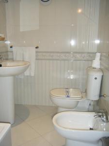 Baño blanco con aseo y lavamanos en Hostal Muriel en Aljaraque