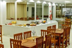 a restaurant with tables and chairs and a counter with food at Pianna Hotel in Buritis