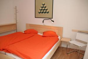 クロスタースにあるMonami Apartments Klosters, Apt. Casa Selva Nr 10のベッドルーム1室(オレンジのシーツと椅子付きのベッド1台付)