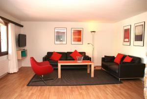 a living room with a couch and a table and a red chair at Monami Apartments Klosters, Apt. Casa Selva Nr 10 in Klosters