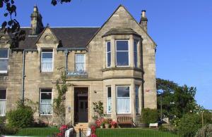 una grande casa di mattoni con una panchina di fronte di Straven Guesthouse a Edimburgo