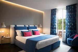 a bedroom with a large bed with blue and red pillows at Hotel Byron in Forte dei Marmi