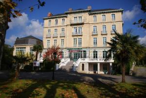 un grand bâtiment avec des palmiers devant lui dans l'établissement Hôtel du Parc, à Salies-de-Béarn