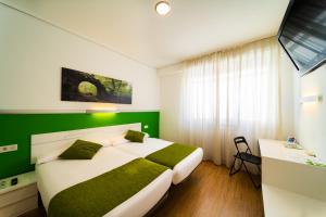 - une chambre avec un grand lit et un mur vert dans l'établissement Hotel Centro Vitoria AutoCheckIn, à Vitoria-Gasteiz
