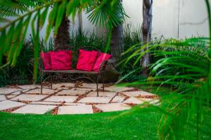 a bench with two red pillows sitting on a lawn at Casa Flora Guesthouse in Pretoria +90 photos