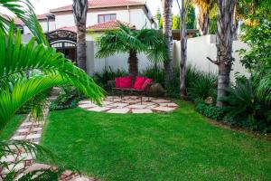 d'une terrasse avec une chaise rouge dans la cour. dans l'établissement Casa Flora Guesthouse, à Pretoria 67 autres photos