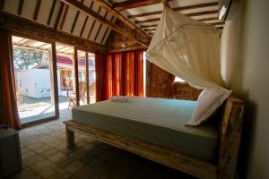 a bedroom with a bed with a mosquito net at Mimpi Bungalow in Gili Meno