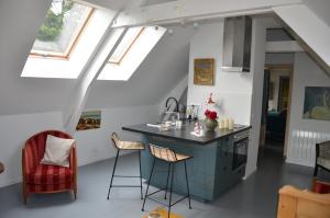 una cocina en el ático con encimera y taburetes en Ô Grenier de l'artiste, en Bazenville