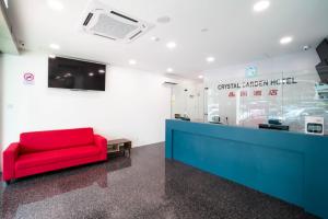 a red couch sits in a waiting room at Crystal Garden Hotel (Tasik Selatan) in Kuala Lumpur