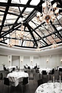 a banquet hall with white tables and chairs and chandeliers at First Hotel Grand in Odense
