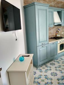 een keuken met blauwe kasten en een tv aan de muur bij La casa Azzurra in Ischia