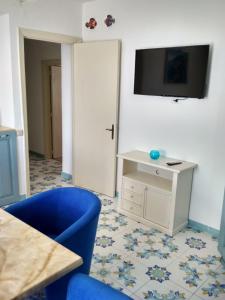 een woonkamer met een blauwe stoel en een tv aan de muur bij La casa Azzurra in Ischia