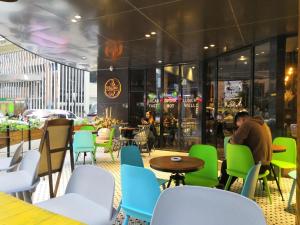 a man sitting at a tables and chairs in a restaurant at Paco Hotel Gangding Metro Guangzhou-Free Shuttle Bus fir Canton Fair in Guangzhou