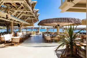 um restaurante na praia com cadeiras, mesas e guarda-sóis em Nostos Beach Boutique Hotel em Balíon