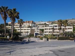 een gebouw met palmbomen voor een straat bij Silvia degli Aregai in Santo Stefano al Mare