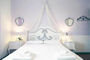 a bedroom with a white bed with two mirrors at Villa Ortensia in Aci Castello