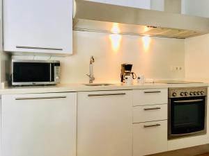 a white kitchen with a sink and a microwave at Apartamentos Santa Faz by Be Alicante in Alicante